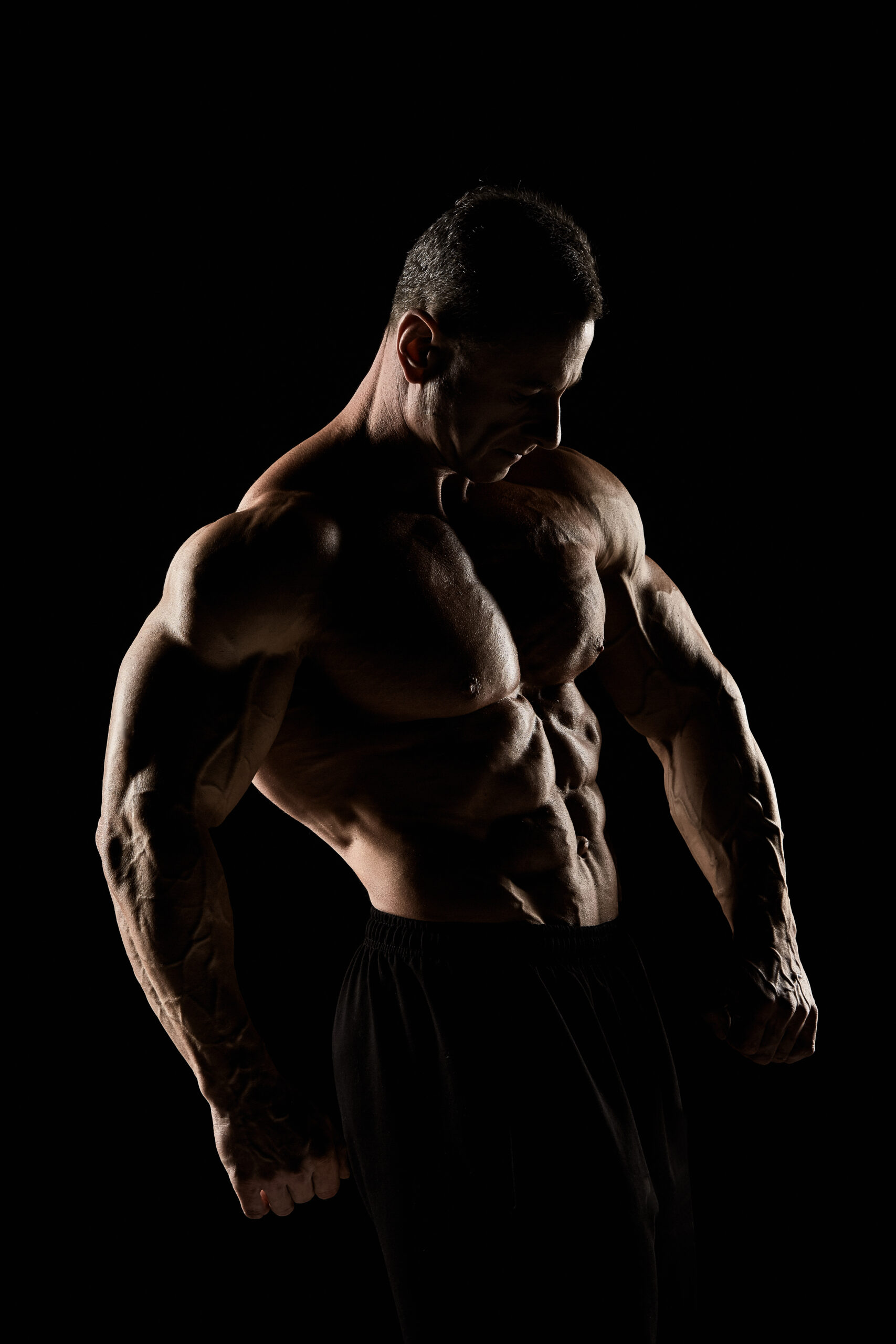 torso of attractive male body builder on black background.